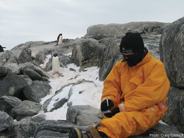 Craig Cormick writing with penguins in the background