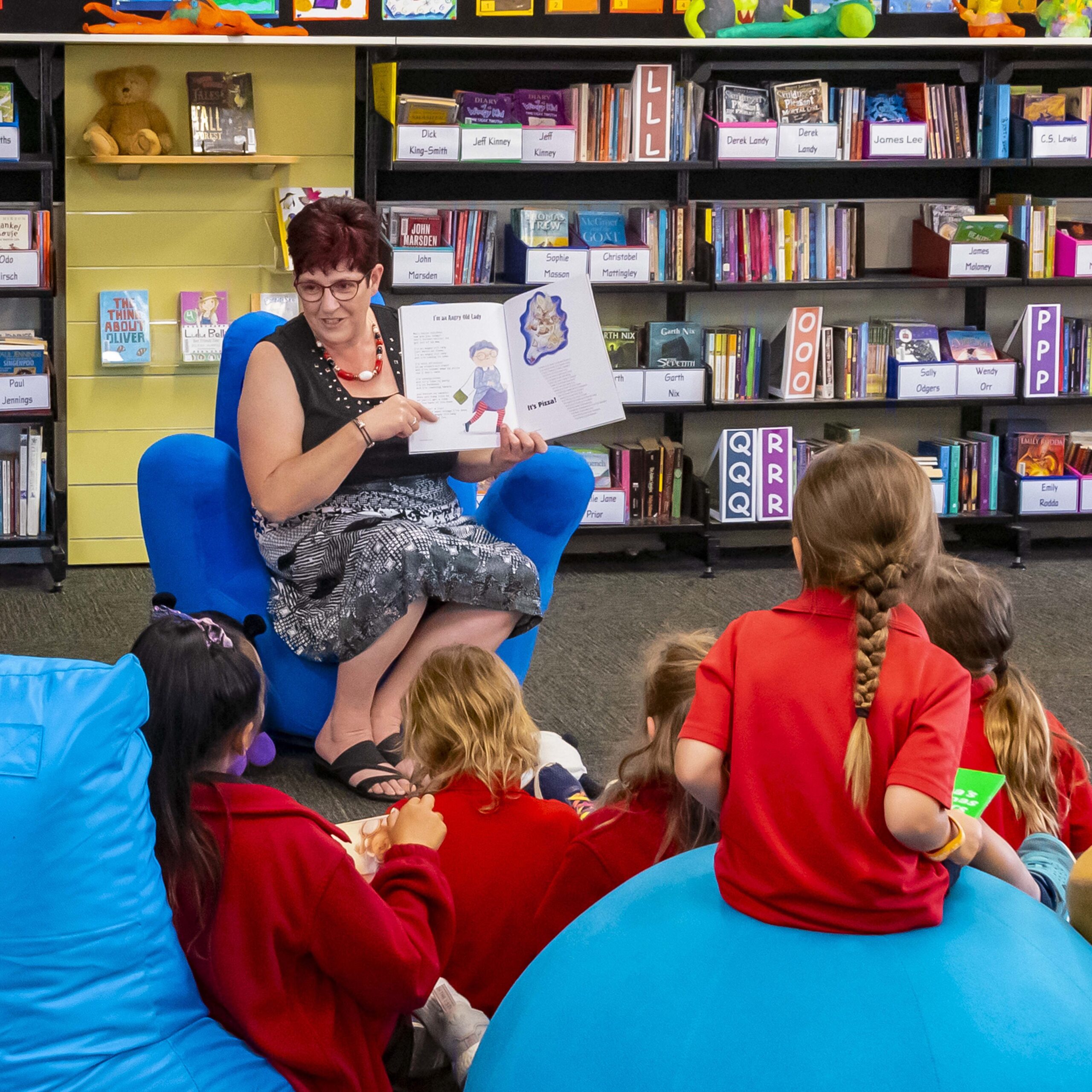 Kellie Nissen of Just Right Words is presenting a writing and reading workshop to a group of primary school children in the school library.