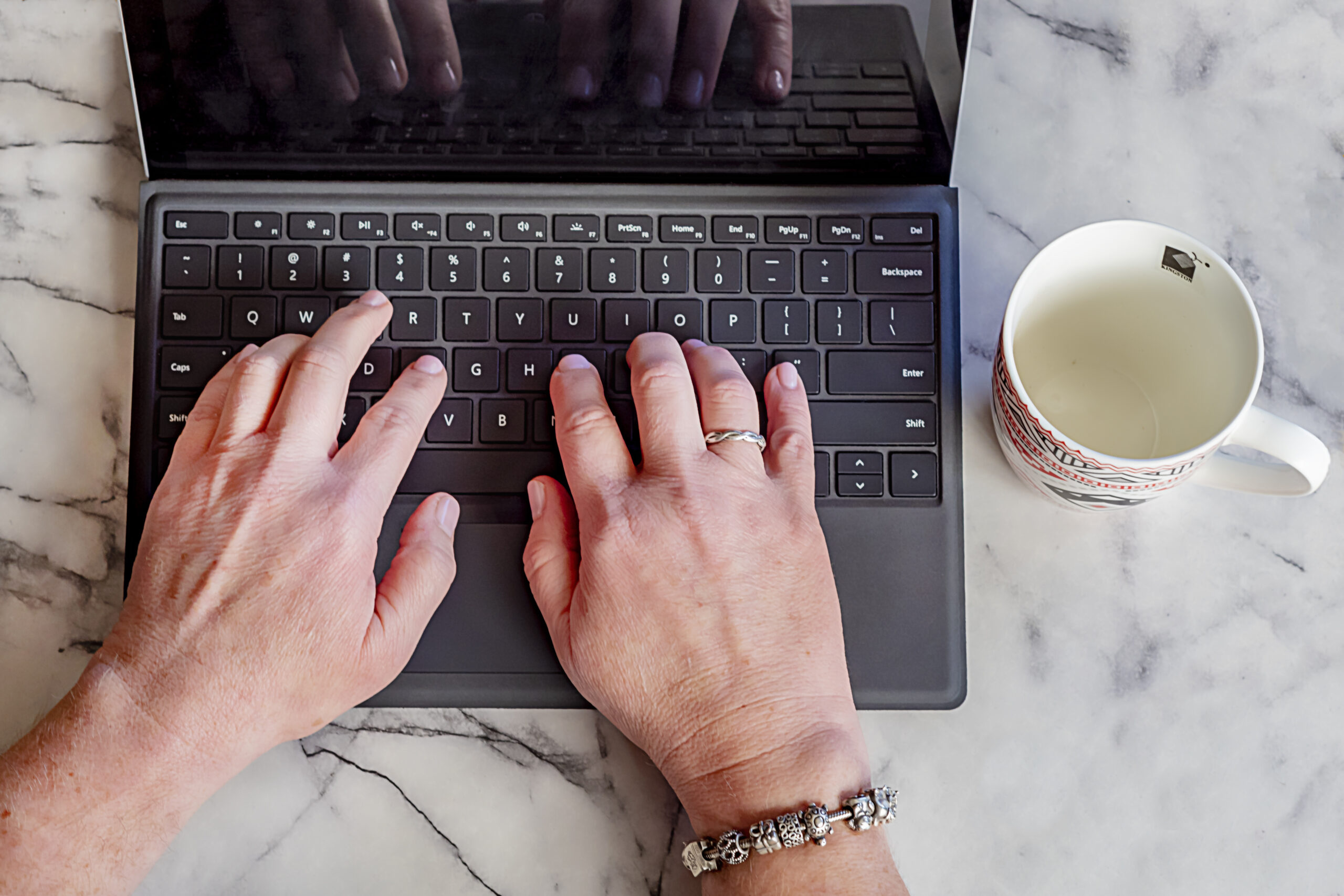 Kellie's hands typing on a laptop keyboard represent her project managing the publication of a client's book. 